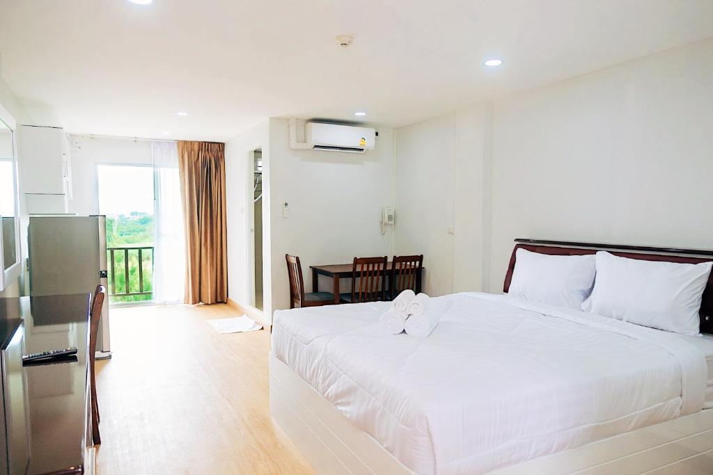 Un dormitorio con una gran cama blanca y una mesa en PT Grand Hotel, en Ban Tha Makham