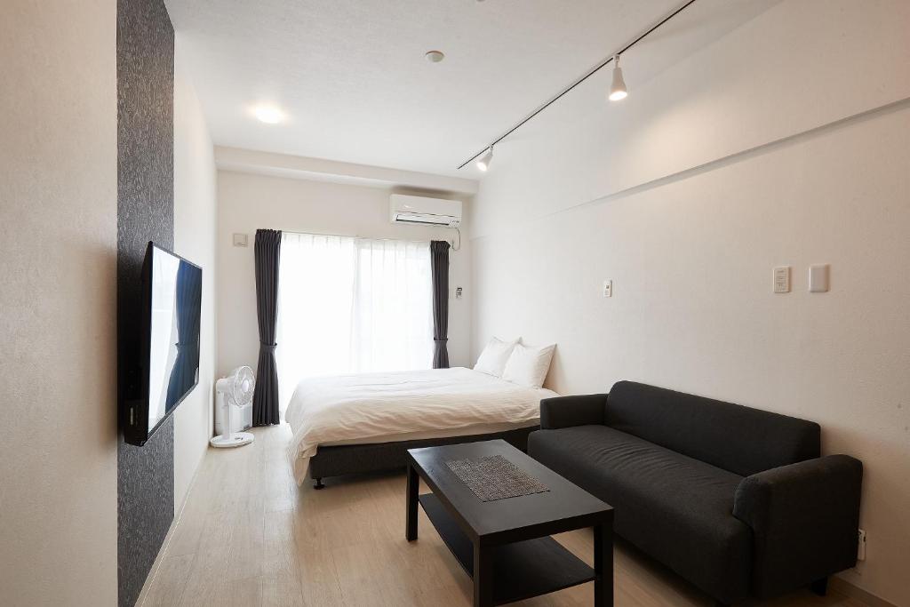 un soggiorno con divano e letto di New Normal Hotel in NAGO ニューノーマルホテルイン名護 a Nago
