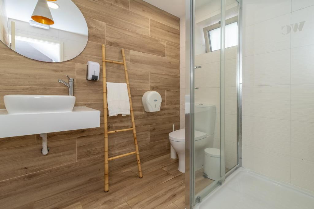 a bathroom with a sink and a toilet and a mirror at Dude Beach Hostel in Figueira da Foz