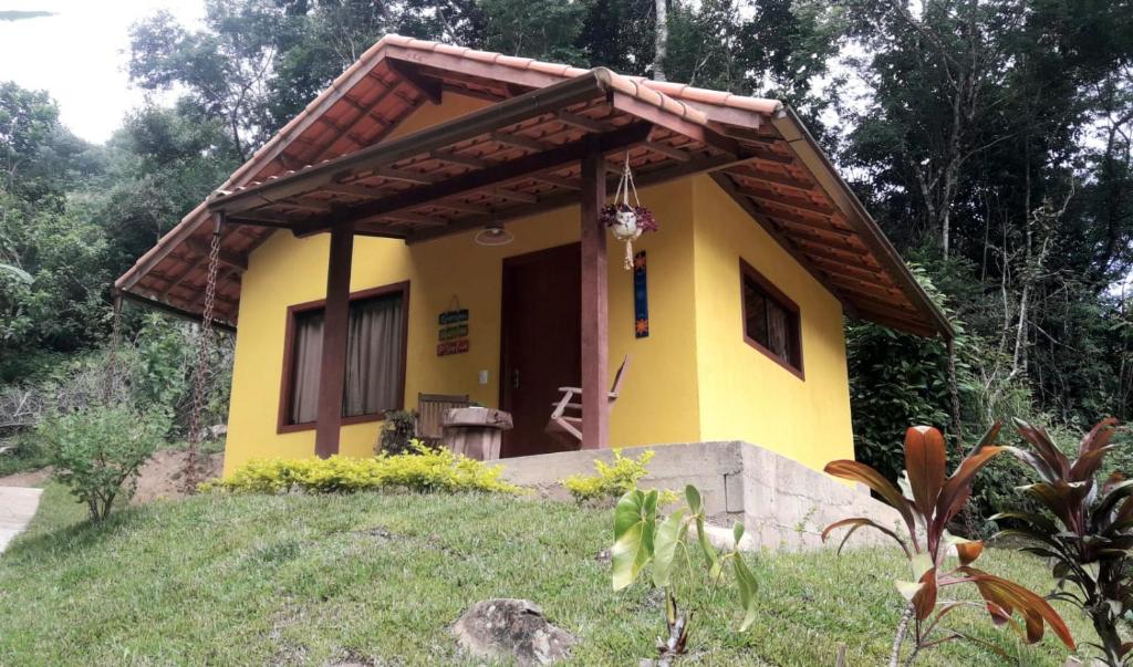 a small yellow house with a roof at POUSADA CHALÉS DA GROTA de SÃO PEDRO DA SERRA- NOVA FRIBURGO in Nova Friburgo