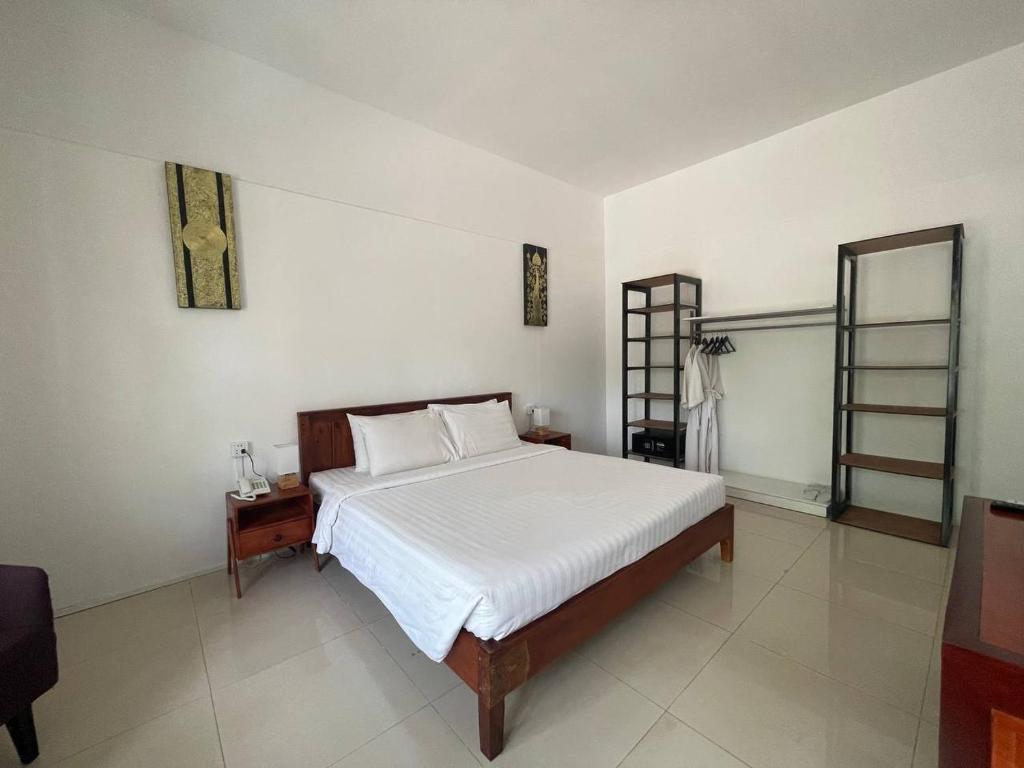 a bedroom with a large white bed and a mirror at La Rivière d' Angkor Resort in Siem Reap