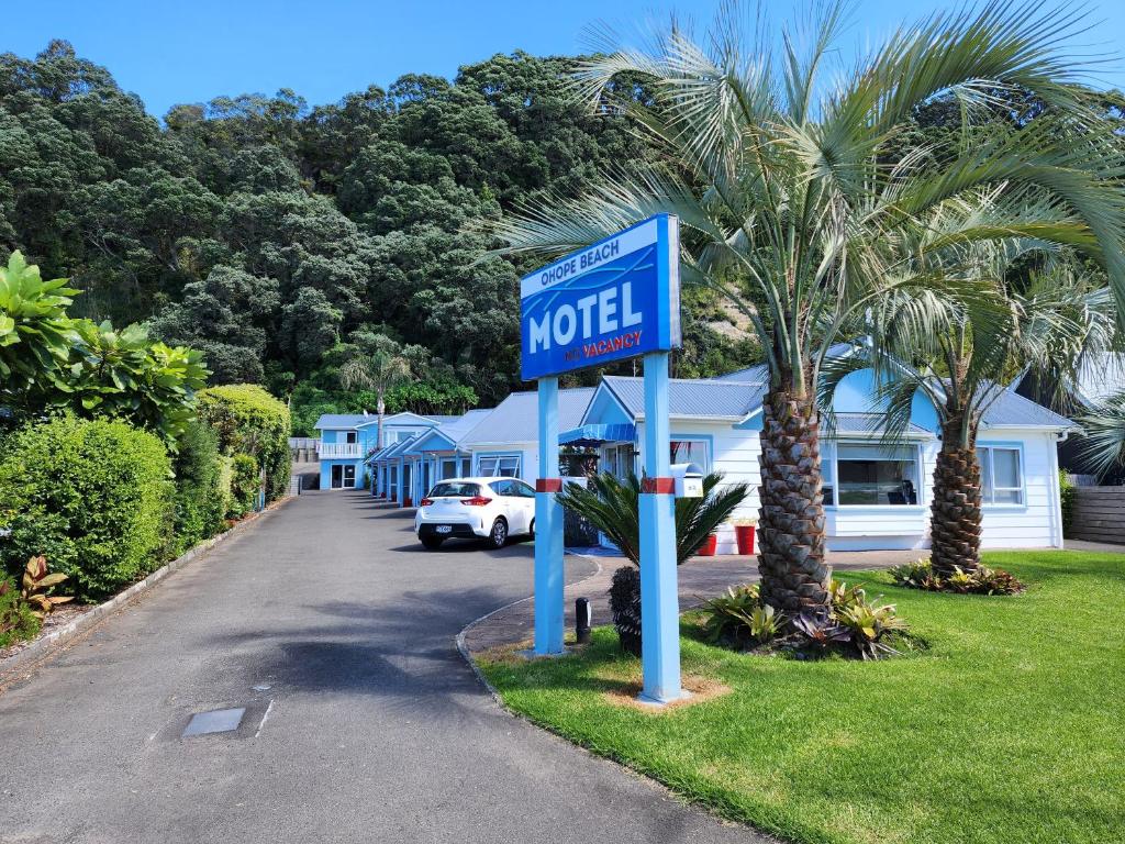 Ohope Beach Motel في شاطئ أوهوب: علامة موتيل أمام منزل به نخلة