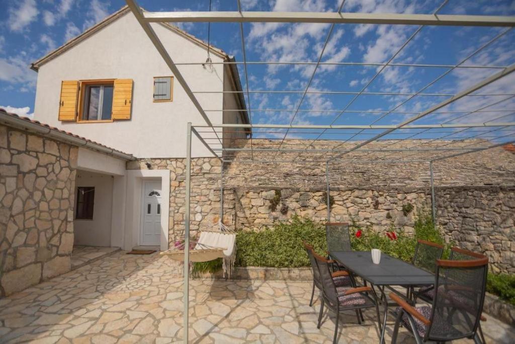 a patio with a table and chairs in front of a house at House MG in Skradin
