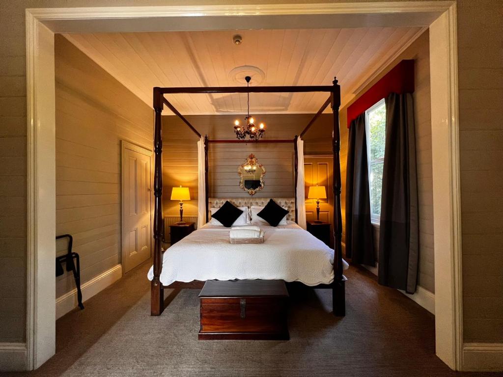 um quarto com uma cama de dossel e um lustre em The Boutique Hotel Blue Mountains em Blackheath
