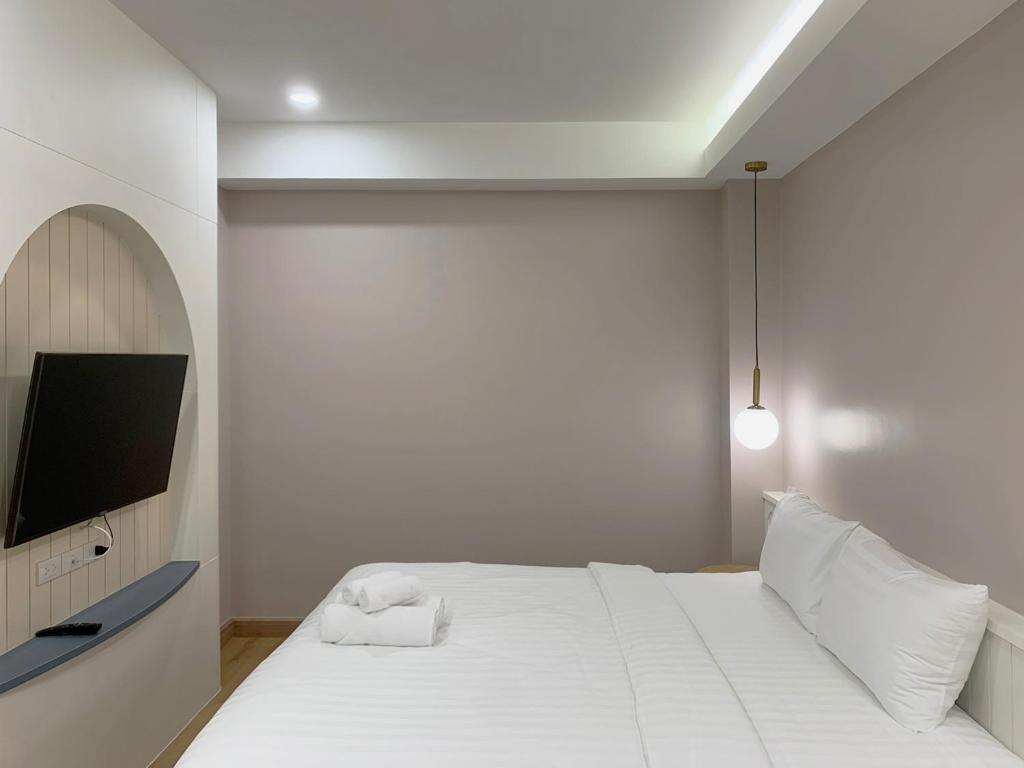een witte slaapkamer met een bed en een televisie bij Moon House BKK Room 3B in Amphoe Phra Khanong