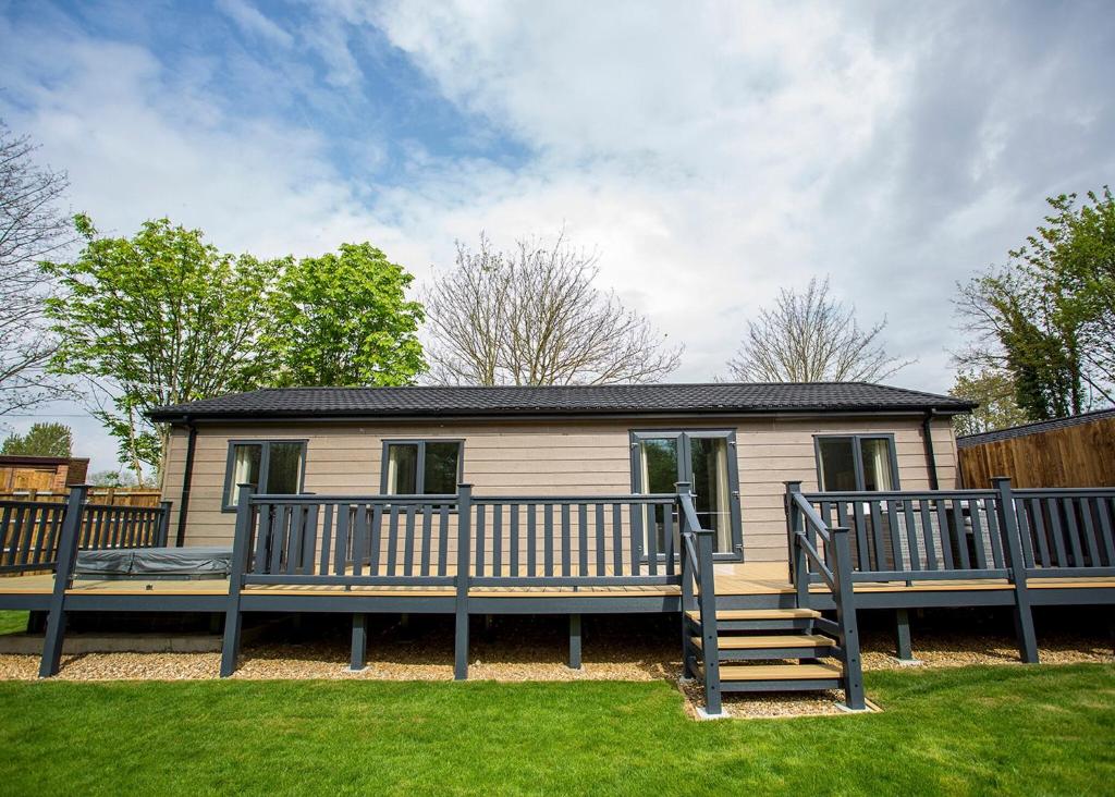 a mobile home with a large deck and a house at Lee Valley in Hoddesdon