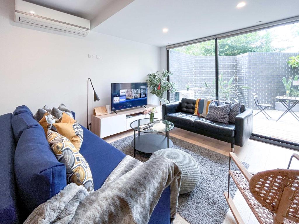 a living room with a blue couch and a tv at Pride Bentleigh Apartment with Private Garden in Melbourne