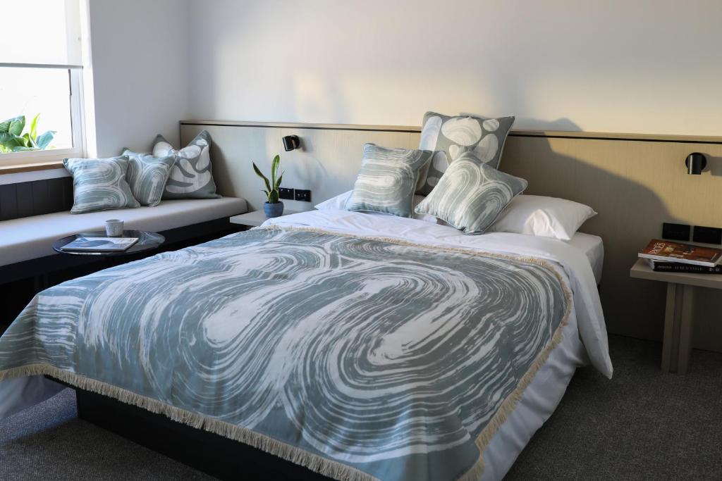 雪梨的住宿－Beach Road Hotel，一间卧室配有一张大床,提供蓝白色的毯子