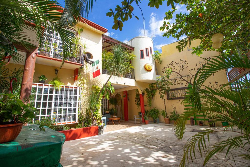 budynek z mnóstwem roślin przed nim w obiekcie La Casa Del Almendro w mieście Playa del Carmen