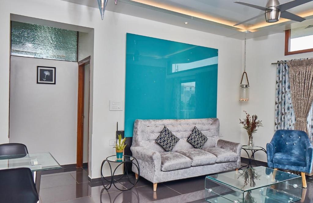 sala de estar con sofá y pared azul en Glass Apartment, en Bangalore