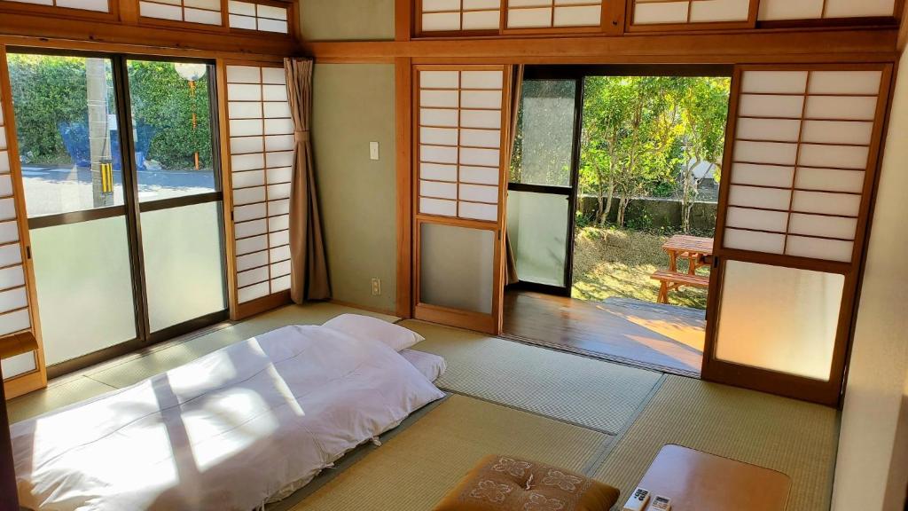 a room with a bed in a room with windows at Guest House Uminokyojyusya - Vacation STAY 83084v in Miyazaki