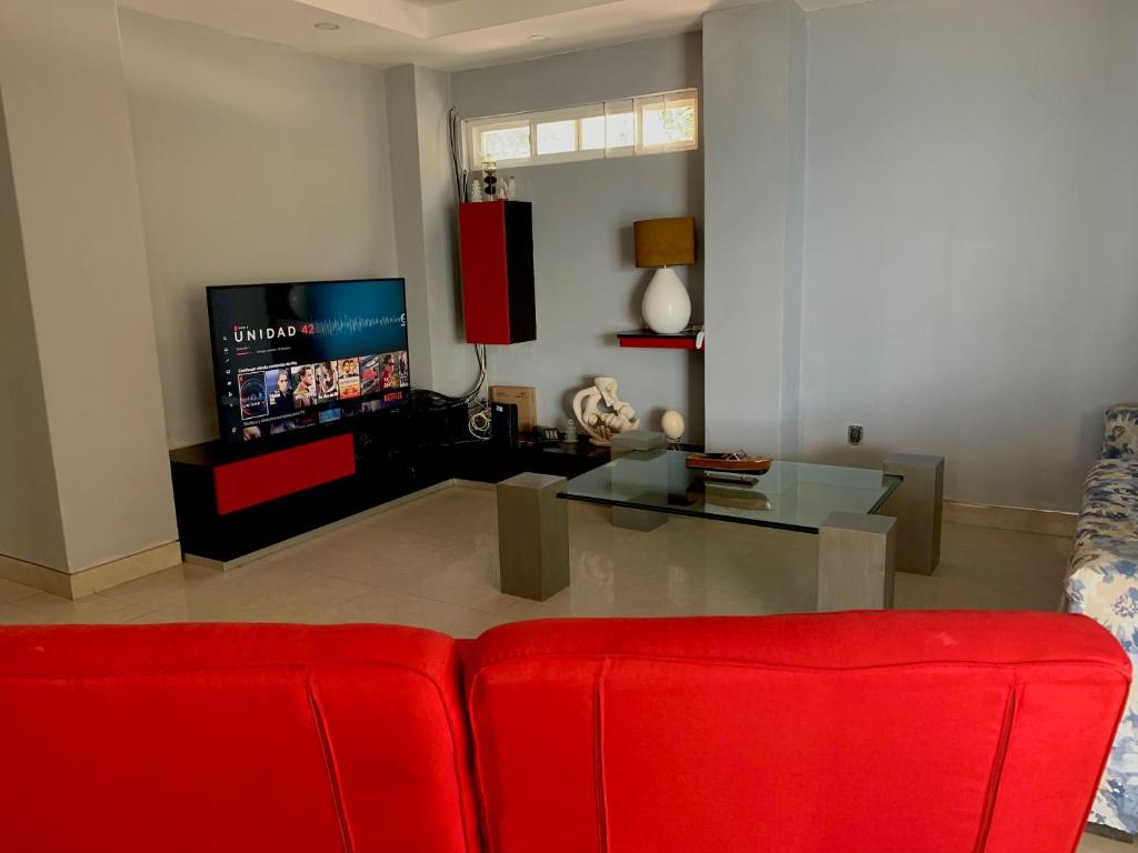 ein Wohnzimmer mit einem roten Sofa und einem TV in der Unterkunft Conchas chinas sunset view in Puerto Vallarta