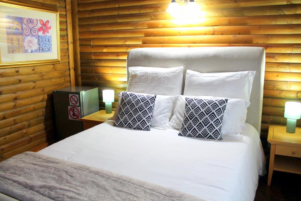 een slaapkamer met een wit bed met kussens bij Ndlovu Log Home Dinokeng in Klipdrift