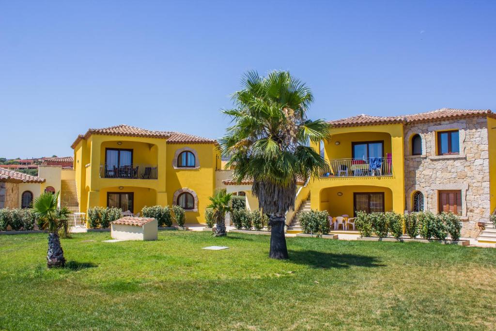a yellow house with a palm tree in front of it at Case Gialle in San Teodoro