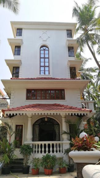 a large white house with a palm tree in front of it at Lucianas Beach Resort in Marmagao