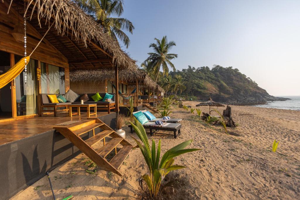 a resort on the beach with chairs and a hammock at Bamboo Yoga Retreat in Canacona