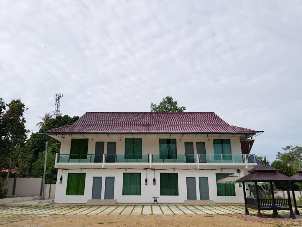 a large white building with green shuttered windows at Akram Homestay in Kota Bharu