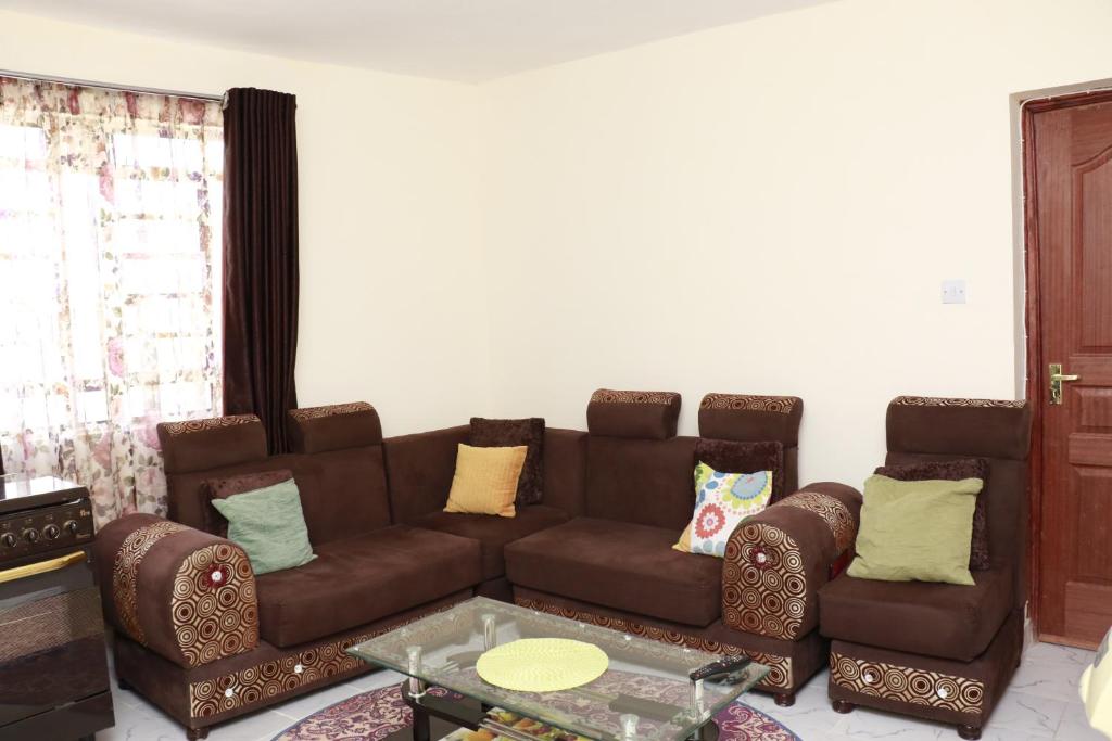 a living room with a brown couch and two chairs at Zanale Stays Furnished Apartment? in Nairobi