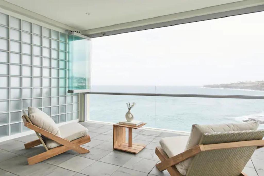 a room with two chairs and a table and a large window at Oceanfront Tamarama Apartment: Best View in Sydney in Sydney