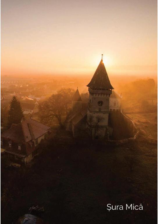 una iglesia en la cima de una colina con la puesta de sol en el fondo en Test GM, en Sibiu