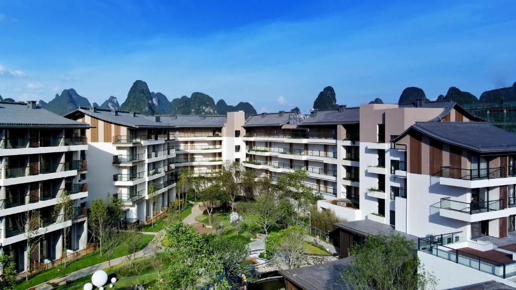 eine Luftansicht von Apartmentgebäuden mit Bergen im Hintergrund in der Unterkunft Ramada Guilin Yangshuo Resort in Yangshuo