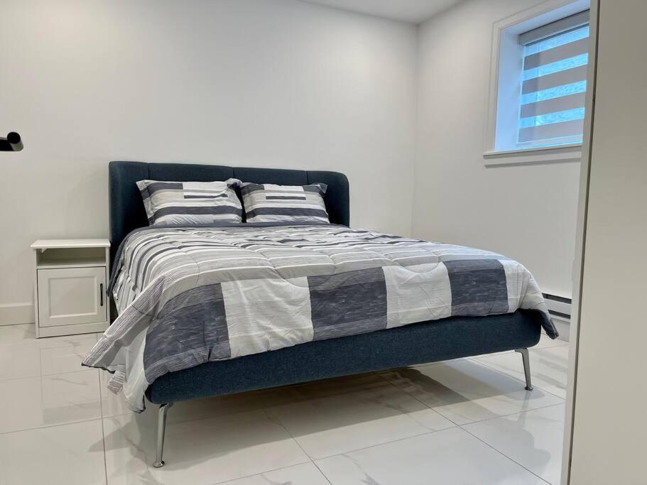 a bedroom with a bed with a black and white blanket at Brand New 2BR Suite with Mini Golf, Children Play Area, and Stunning Patio in Aldergrove in Aldergrove