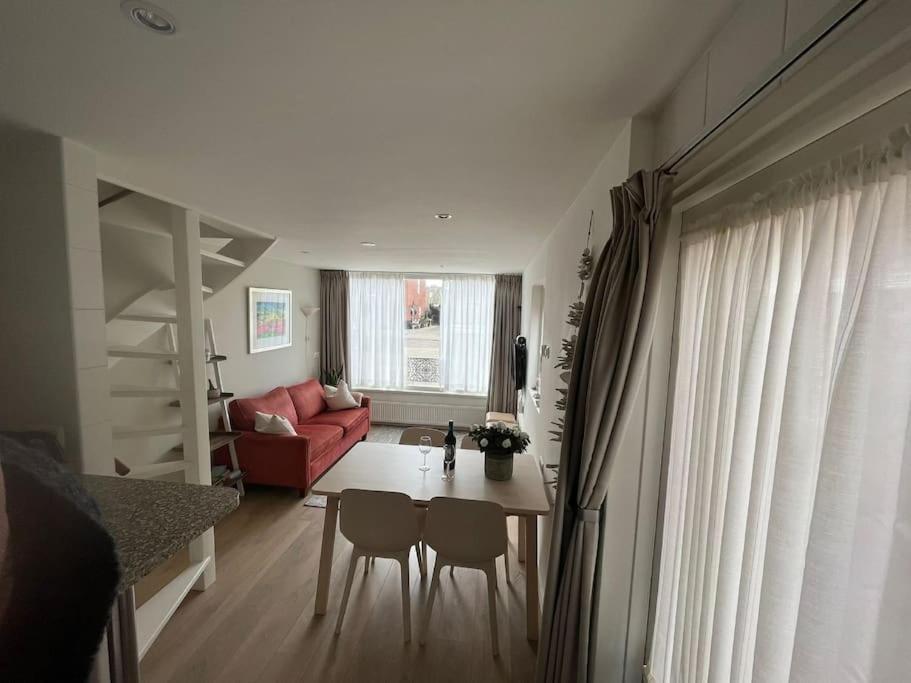 uma sala de estar com uma mesa e cadeiras e um sofá vermelho em Zomerhuis Toda Cambia dicht bij strand em Noordwijk aan Zee