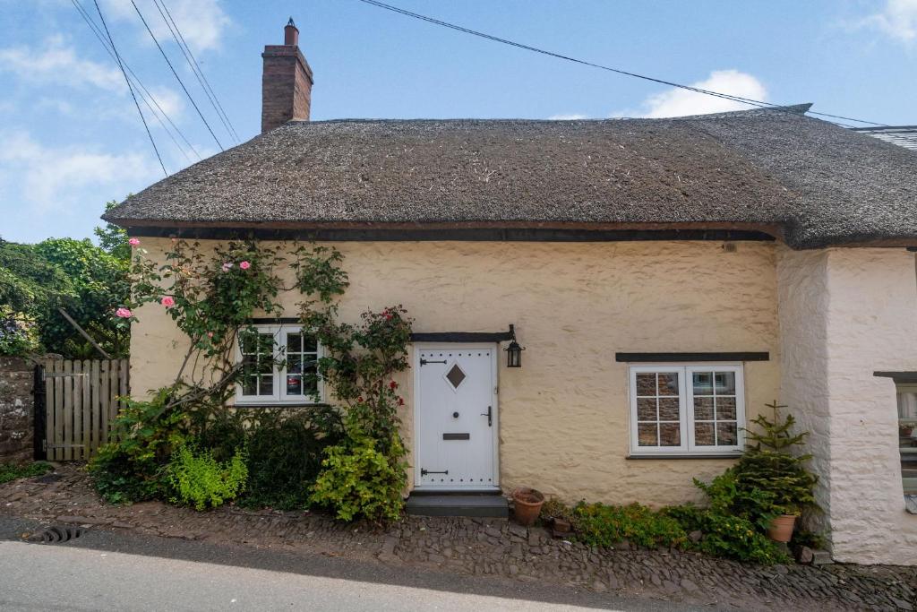 a small cottage with a white door and flowers at 4 Bishops Cottages in Minehead