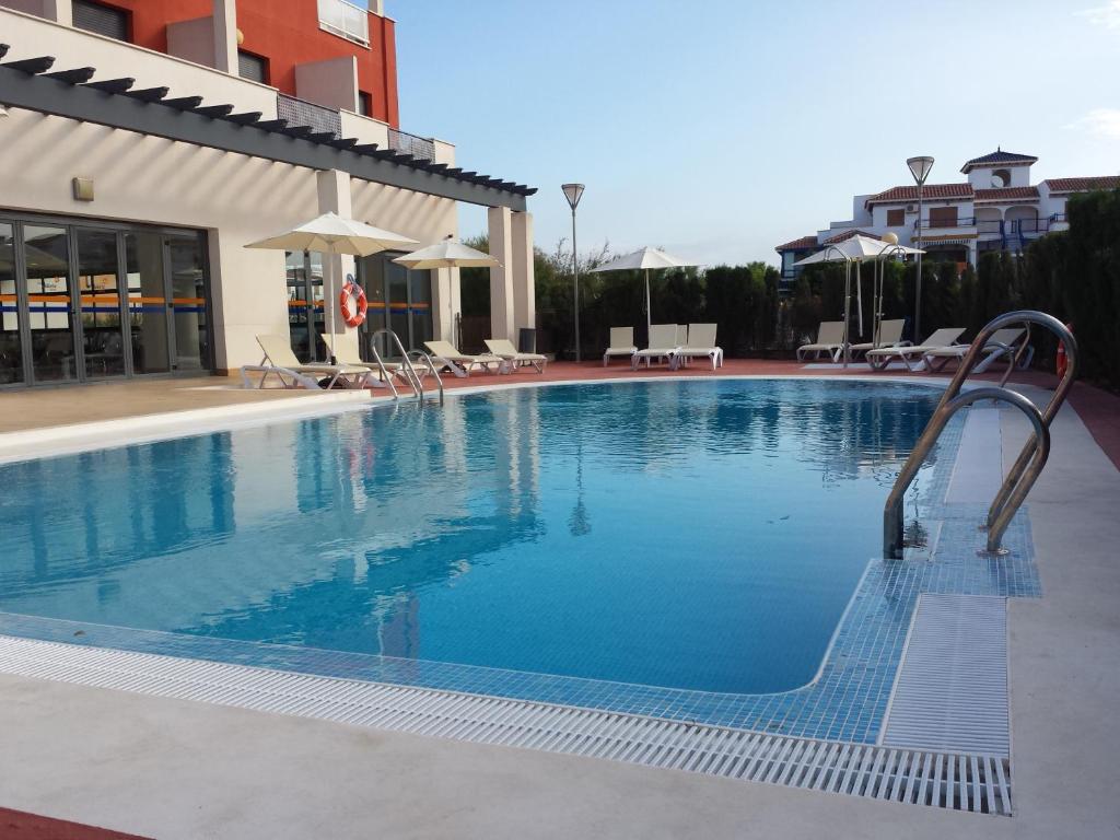 una gran piscina con sillas y sombrillas en Hotel Adaria Vera en Vera