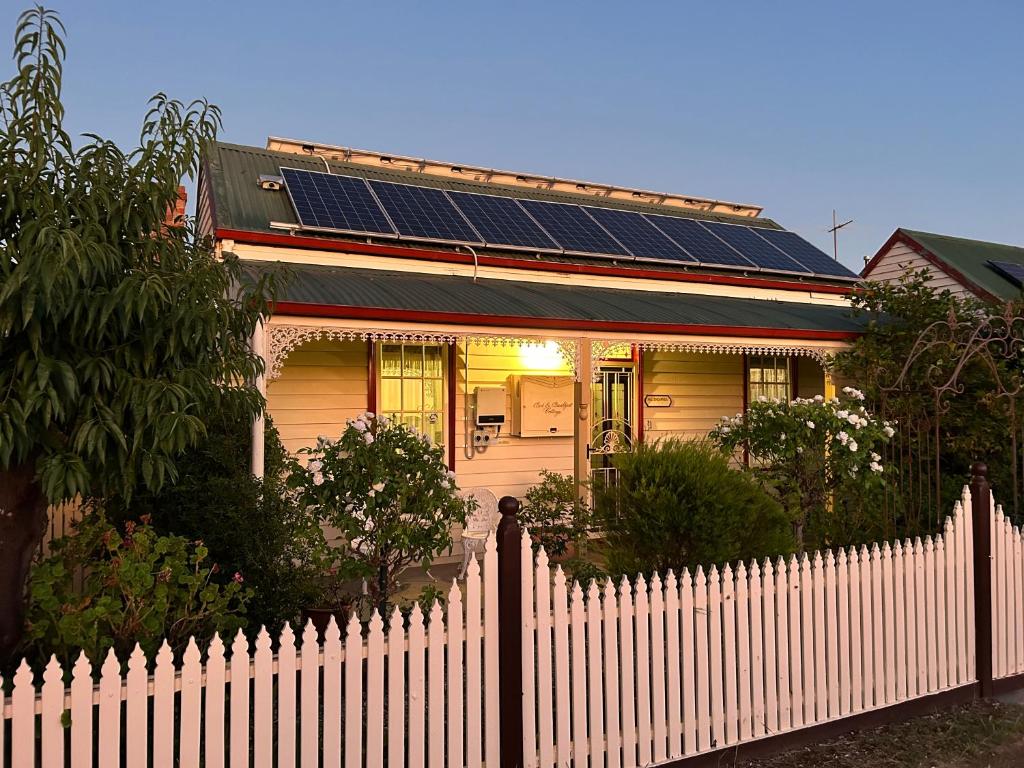 a white fence in front of a house with solar panels at Foundry Cottages in Rutherglen