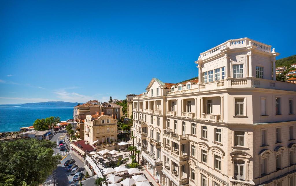 a building on a street with the ocean in the background at Hotel Bellevue - Liburnia in Opatija