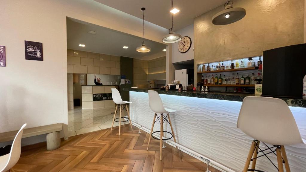 a bar with white chairs and a counter at Hotel Atlanta in Patra