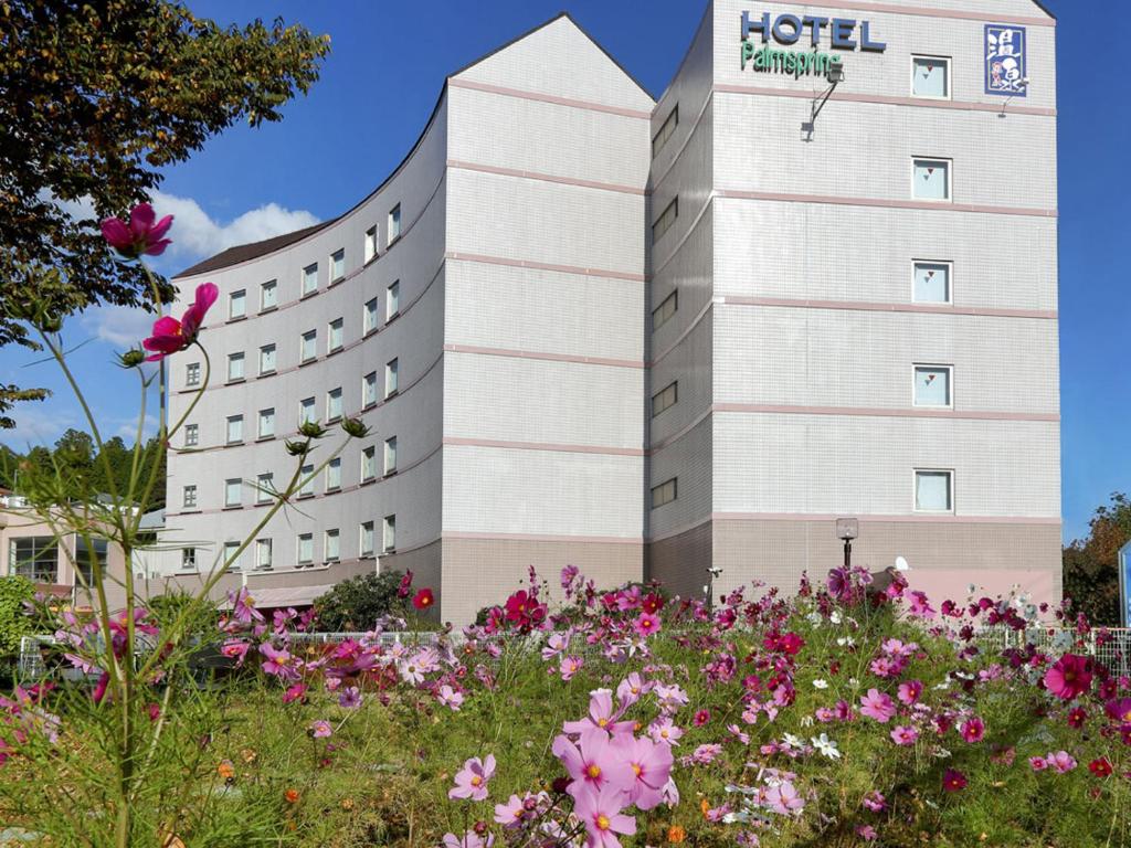 a hotel with a field of flowers in front of it at Hotel Palm Spring in Iwaki