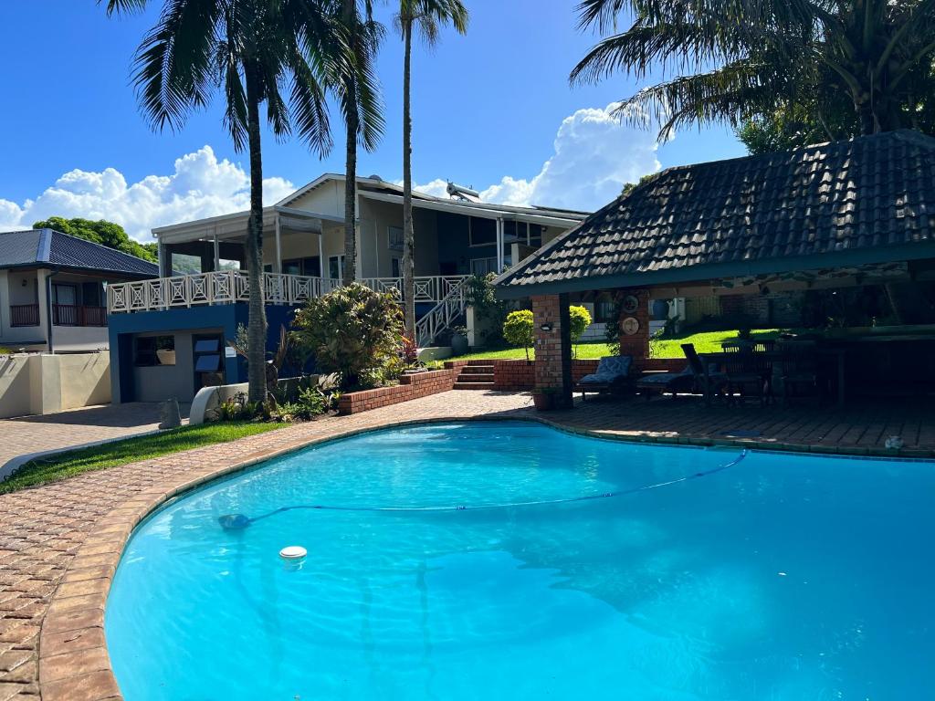 a blue swimming pool in front of a house at Whalesong Guest House in St Lucia