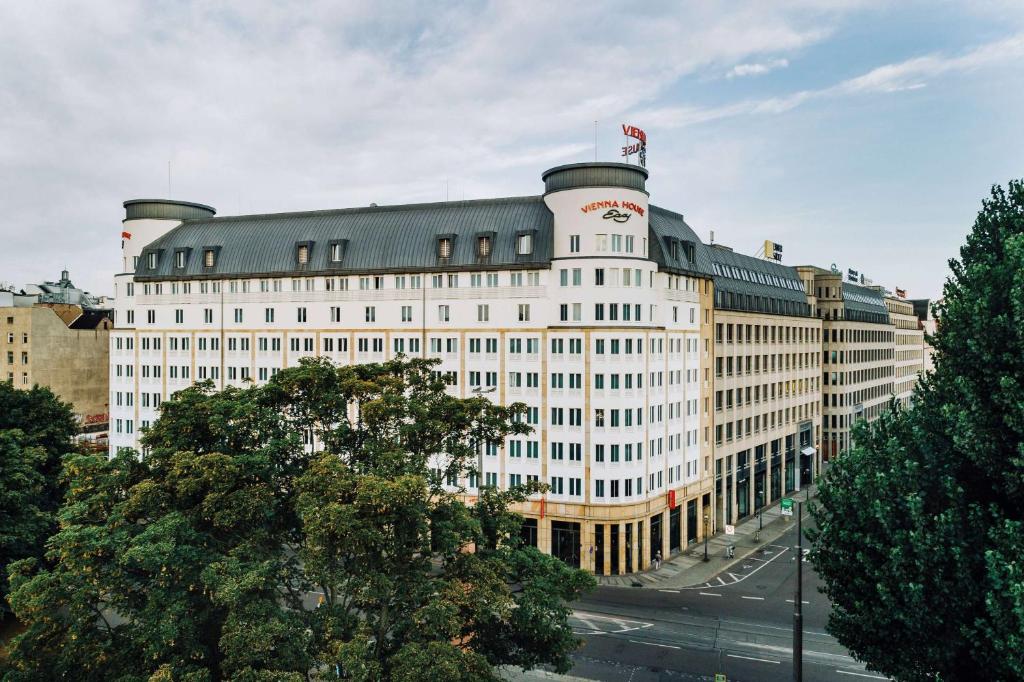 un gran edificio blanco con una bandera encima en Vienna House Easy by Wyndham Leipzig, en Leipzig