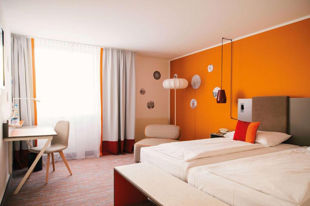 una camera d'albergo con letto e scrivania di Vienna House Easy by Wyndham Limburg a Limburg an der Lahn