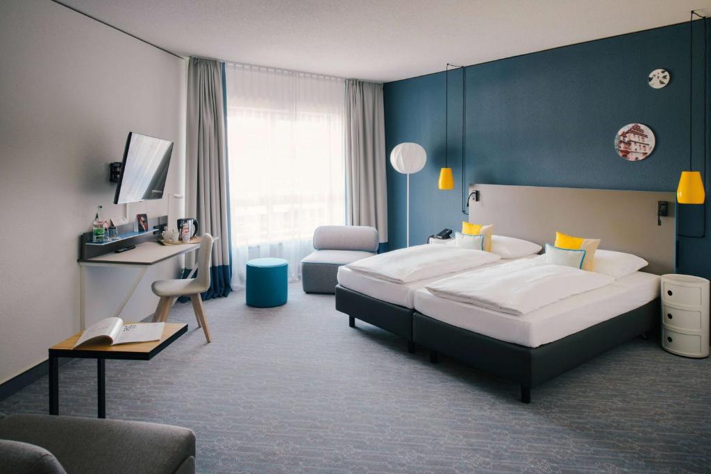 um quarto com uma cama grande e uma parede azul em Vienna House Easy by Wyndham Coburg em Coburgo