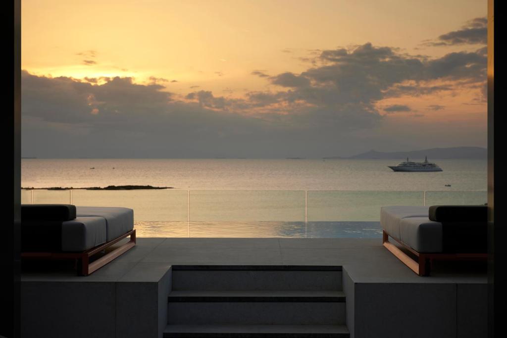 een kamer met uitzicht op de oceaan en een boot bij Dusit Suites Athens in Athene