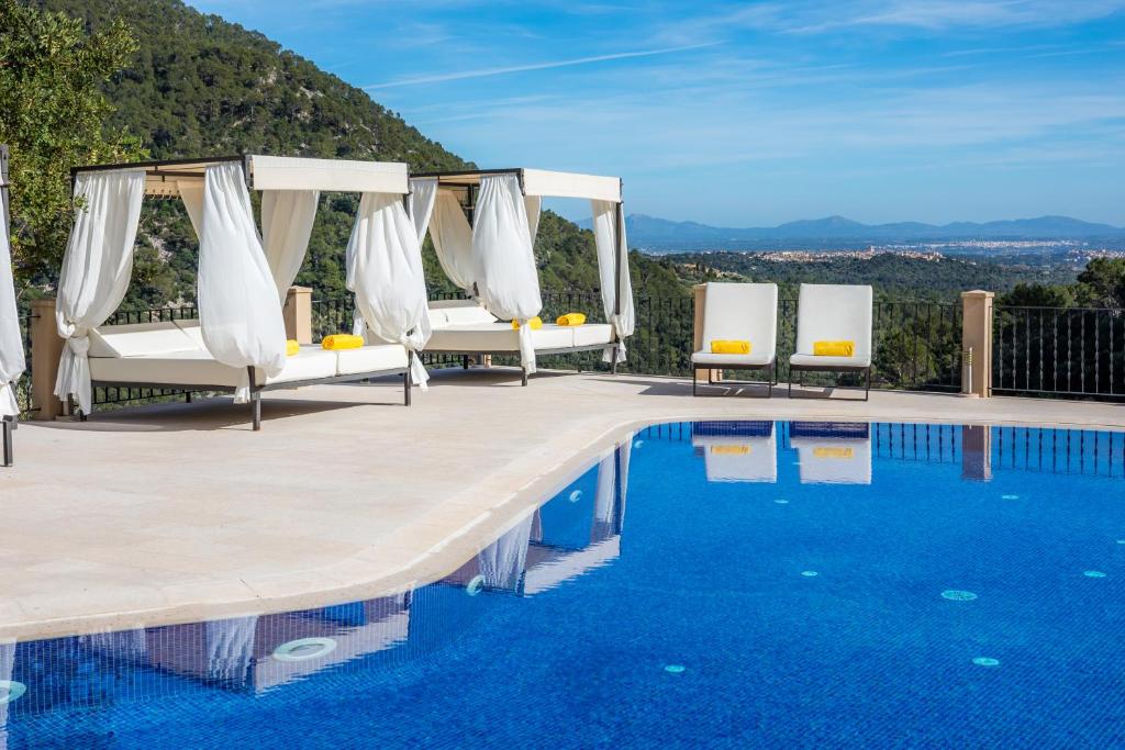 una piscina en un complejo con sillas blancas y vistas en Finca Albellons, en Binibona