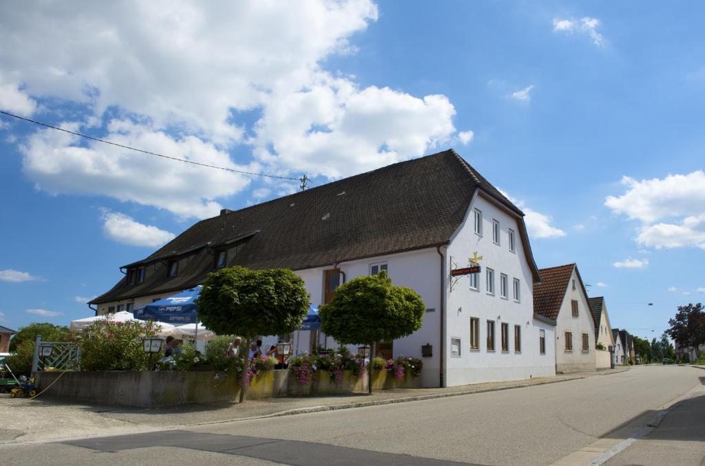 a white building with a black roof on a street at Gasthof zum Kreuz in Neuenburg am Rhein