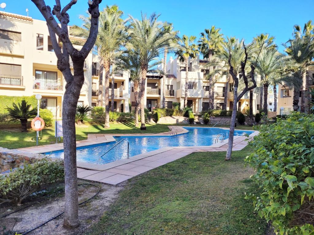 uma piscina com palmeiras em frente a um edifício em El Oasis de las Palmeras @ Roda Golf & Beach resort em San Javier