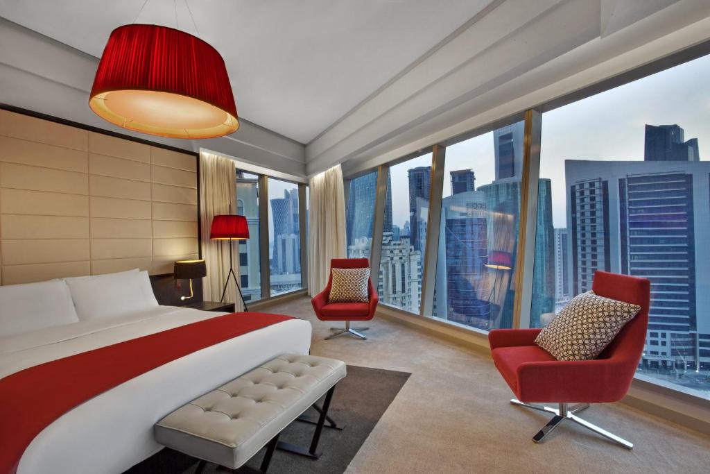 1 dormitorio con 1 cama grande, sillas y ventanas en W Doha Residences, en Doha