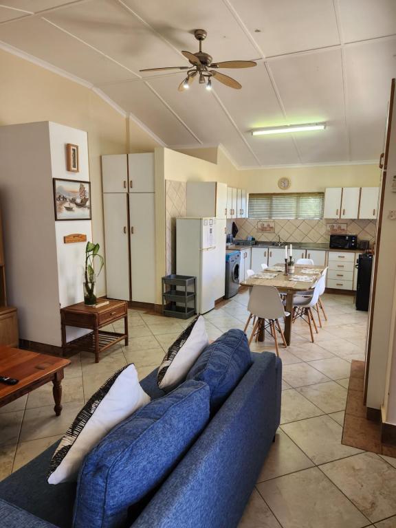 a living room with a blue couch and a kitchen at Aloe Self Catering in Port Shepstone