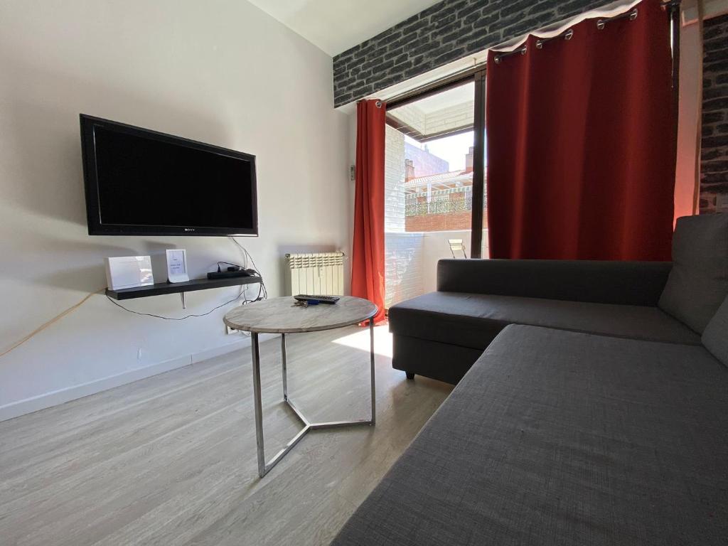 a living room with a couch and a tv and a table at Apartamento Cuzco in Madrid