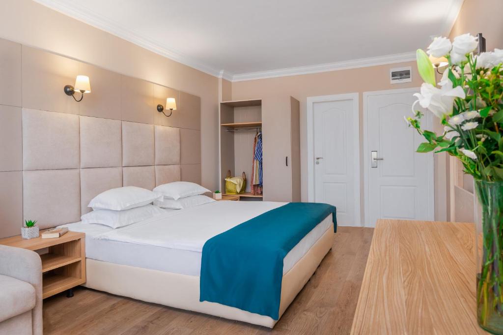 a bedroom with a large white bed and a vase of flowers at Veramar Hotel - All Inclusive & Free Beach in Kranevo