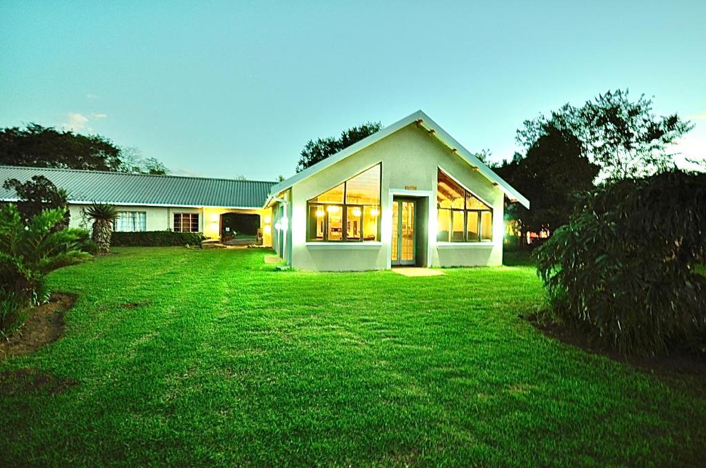 dom z dużym trawnikiem przed nim w obiekcie Drakensberg Inkosana Lodge w mieście Champagne Valley