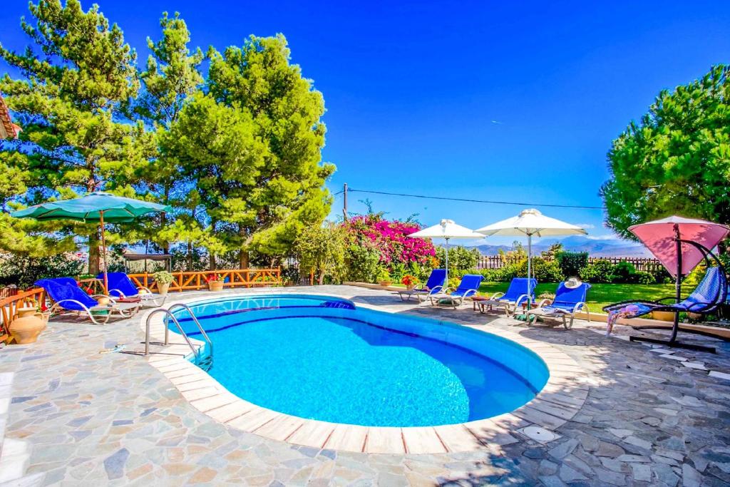 a swimming pool with blue chairs and umbrellas at Villa Agapi Episcopi in Episkopí