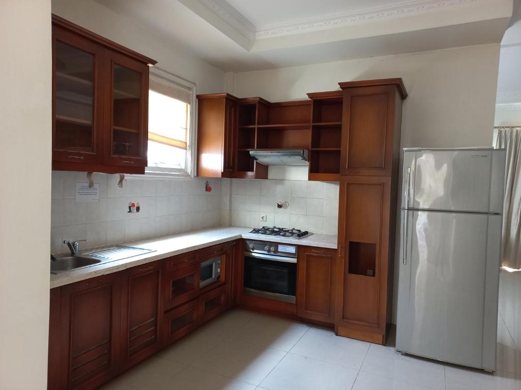 een keuken met houten kasten en een witte koelkast bij Margot Apartment Pondok Indah in Jakarta