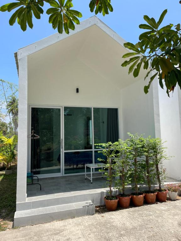a white house with a patio with plants at Mook Ing Lay in Ko Mook