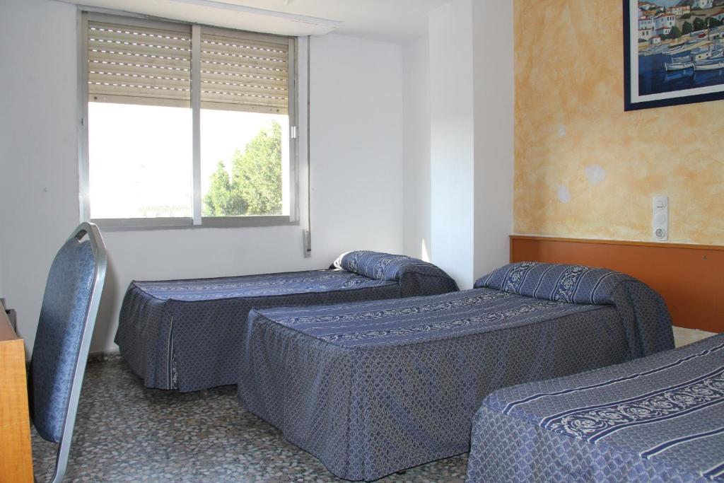 a room with three beds and a window at Hostal Mengual in Gandía